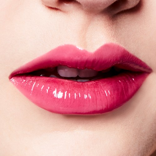 Close-up of lips with glossy pink lipstick and slightly parted teeth.