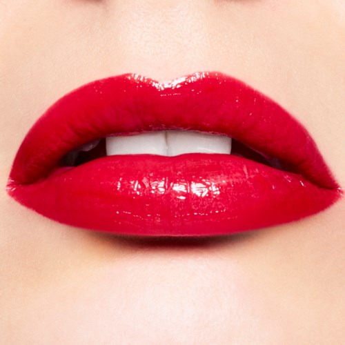 Close-up of bright red lips with slightly parted teeth and shiny lipstick.