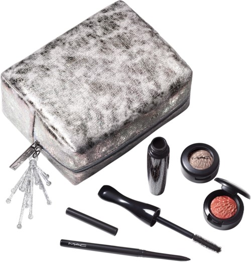 En silverfärgad, sammetsliknande necessär med sminkprodukter som blush, mascara, läppstift och appliceringsverktyg utanför den.