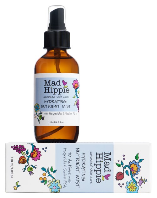 En ravfarget sprayflaske merket 'Mad Hippie Hydrating Nutrient Mist' med blomsterillustrasjoner, plassert over en matchende eske.