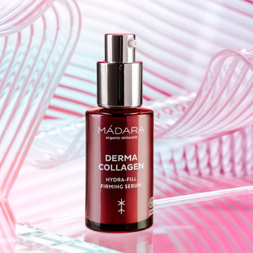 Röd serumflaska med silverpump, märkt 'MÁDARA Derma Collagen Hydra-Fill Firming Serum', på en rosa och vit bakgrund.
