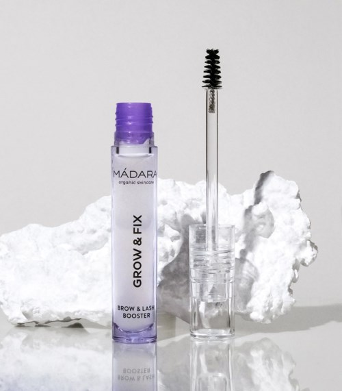 En liten lila flaska märkt 'Brow & Lash Fix' med en applikator står bredvid ett molnliknande vitt föremål.