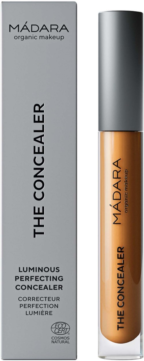 Ein beiger Concealer in einer kleinen Glasflasche mit grauem Deckel, neben einer grauen Schachtel mit "MADARA" und "The Concealer".