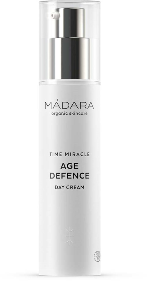 En vit flaska med en silverpump märkt 'MÁDARA Age Defence Day Cream', den ser modern ut.