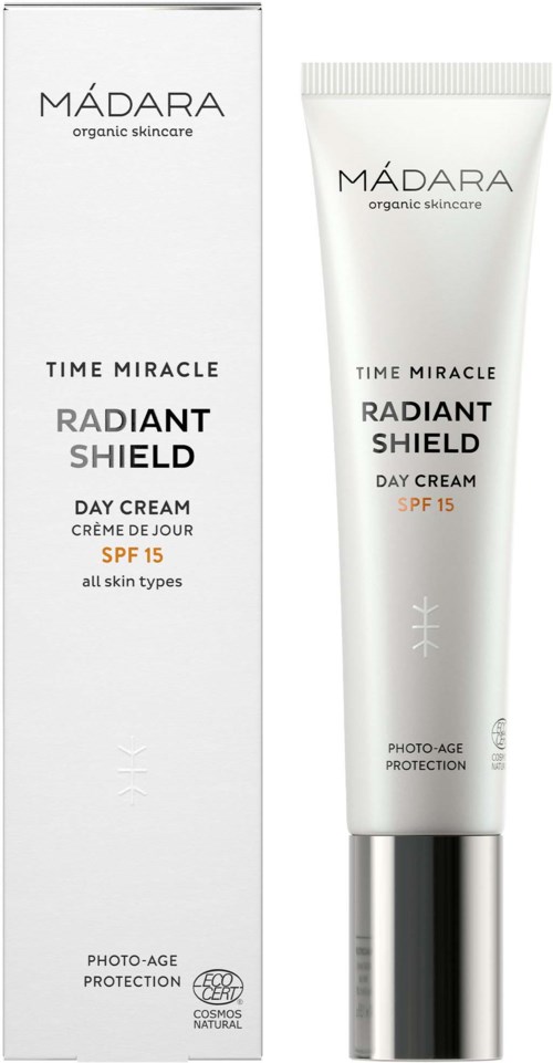 Een witte tube met een zilveren dop en bijpassend doosje die een huidverzorgingsproduct genaamd Madara Radiant Shield Day Cream toont.
