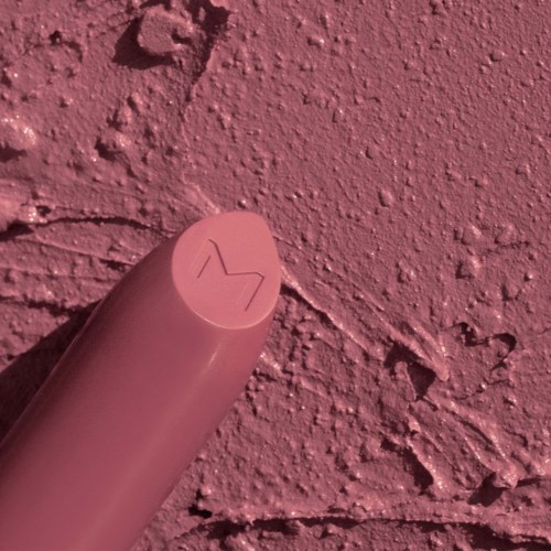 En rosa cylindrisk genstand på en tekstureret rosa væg. Toppen har et lille, stiliseret mærke eller pil. Scenen er ensartet rosa.