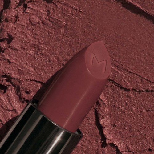 A lipstick with the Mario logo engraved on the case, placed against a textured red background.