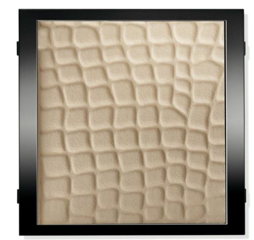 En svart kvadratram omger en beige texturerad yta med ojämna geometriska mönster.