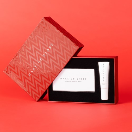 A red box with a lipstick and a small white booklet inside on a red background.