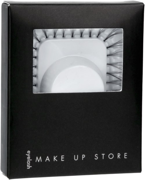 En svart låda med ett genomskinligt fönster som visar falska ögonfransar inuti. Kartongen har 'MAKE UP STORE' skrivet på sig.
