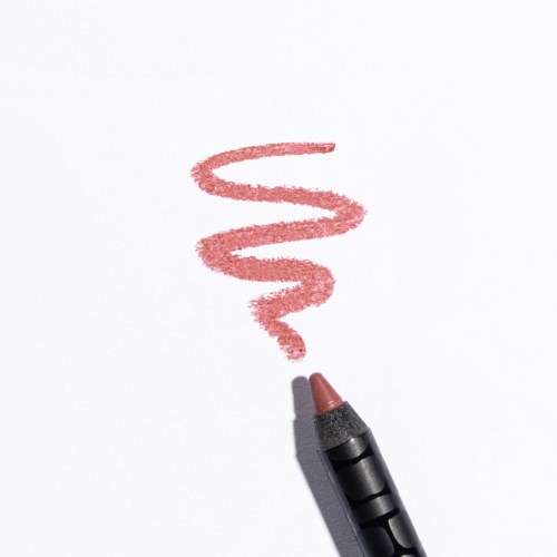 A brown crayon draws a wavy line on white paper.