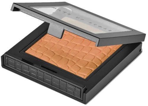 A makeup compact with a mirror, containing bronze-colored powder with a textured pattern.