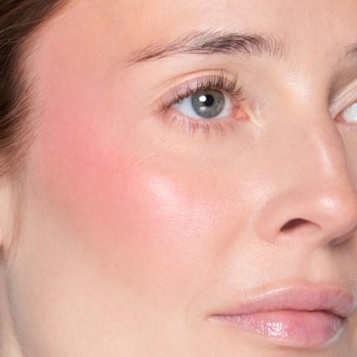 Nahaufnahme eines Frauen Gesichts mit glatter Haut, blauem Auge und natürlichen Lippen.