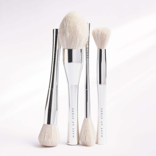 Three makeup brushes with white bristles and silver handles stand upright against a white background.