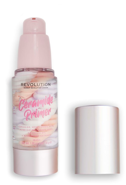 A pink and clear bottle of Revolution Ceramide Primer with a white cap nearby.