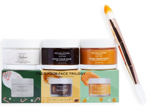 Set of skincare jars and a brush, labeled "Feed Your Face Trilogy." The jars are white, brown, and orange.
