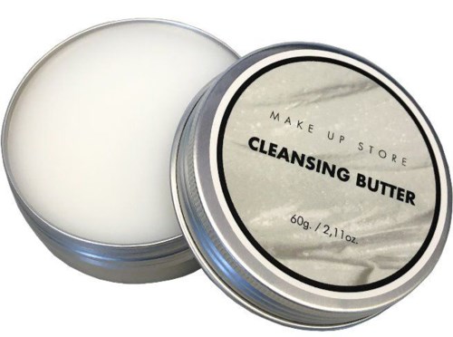 En rund metallburk öppen som visar vit rengöringsfett, med en etikett på locket som säger 'Cleansing Butter'.