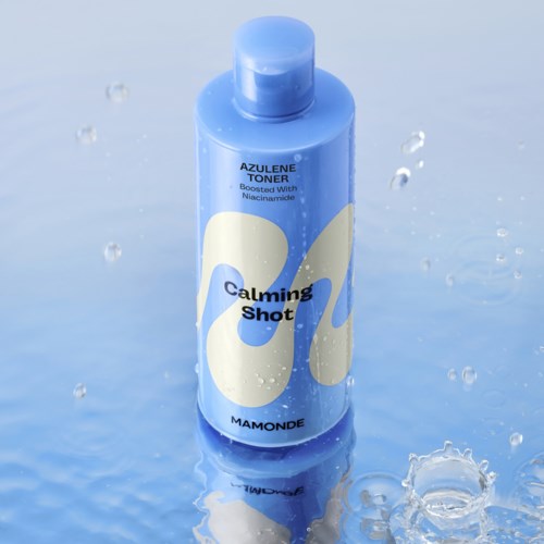 A blue bottle labeled 'Calming Shot' with water droplets around it and a reflective surface.