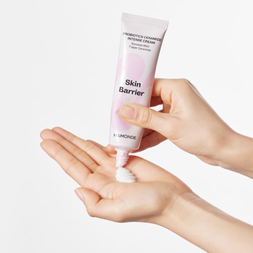 Eine Hand drückt weiße Creme aus einer Tube mit der Aufschrift 'Skin Barrier' auf die Handfläche.