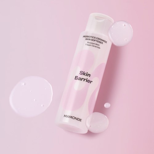 En hudvårdsprodukt kallad Skin Barrier av Mamonde, med rosa och vit förpackning, omgiven av klara sfärer på en rosa bakgrund.