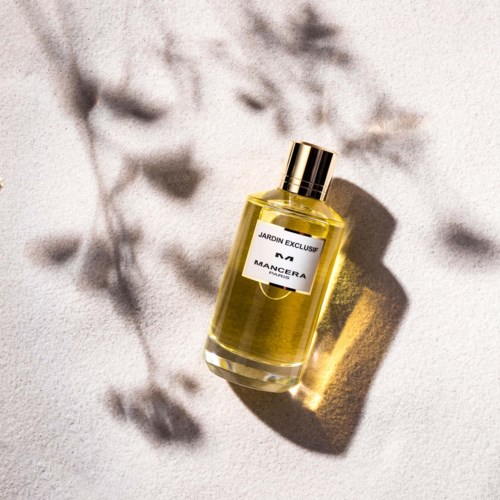 En parfume flaske mærket 'Jardin Exclu' med skygge og blødt baggrund.