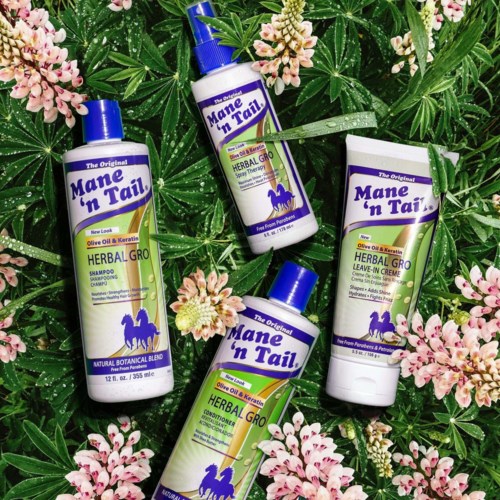 Four Mane 'n Tail herbal grooming hair products placed among pink flowers and green leaves.