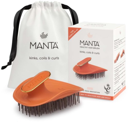A hairbrush with black bristles in front, orange with a gold plate, white bag, and box with product image.