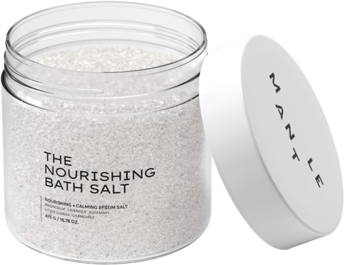En klar krukke med nærende badebadsalt med et hvitt lokk, merket med produktbeskrivelse og duftnoter.