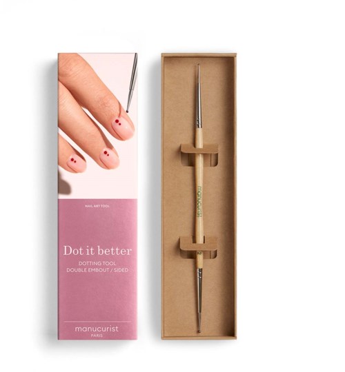A nail dotting tool with two ends inside a cardboard box, with a pink and white product box showing a finger with red dots.