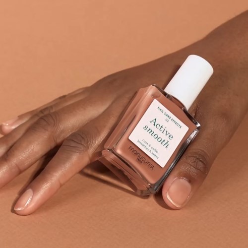 A hand with neatly manicured nails holds a skincare bottle labeled 'Active Smooth' from Mary Kay.