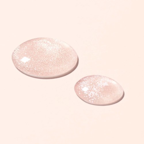 Two shiny, glittery, pinkish pills or tablets on a light background.