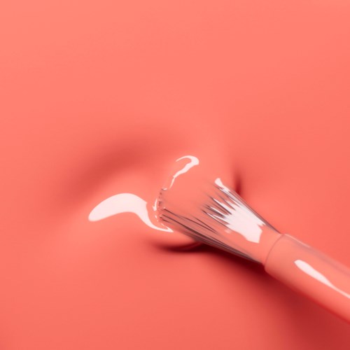 Meikkisivellin levittää valkoista voidetta pinkkiin ihoon.