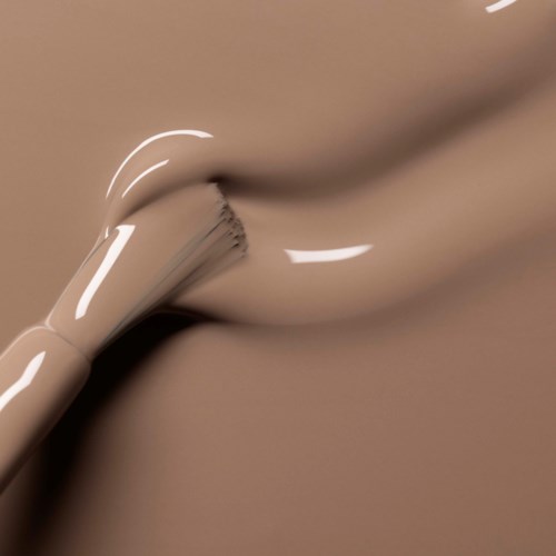 A close-up of smooth, shiny, beige-colored liquid or gel flowing and creating soft curves.