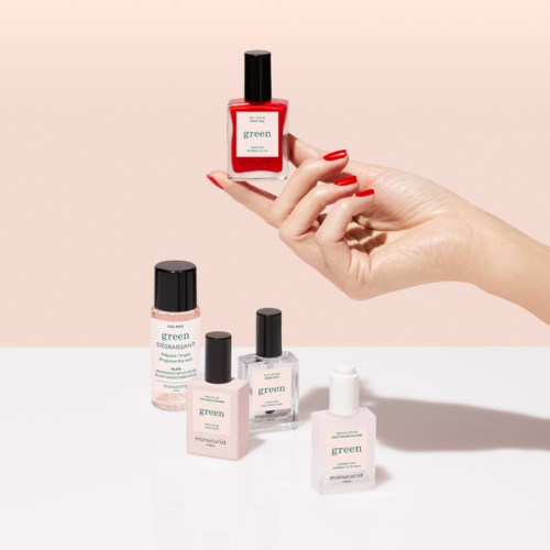 Fünf Flaschen Nagellack und Entferner auf weißer Oberfläche, mit einer Hand, die eine rote Flasche hält.