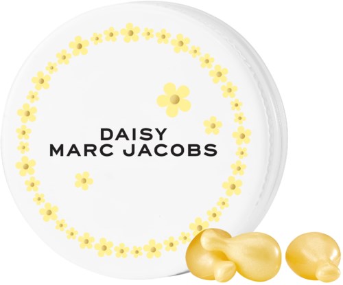 A white plate with yellow flower designs and the names Daisy and Marc Jacobs in the center. Gold-colored candies are at the bottom.