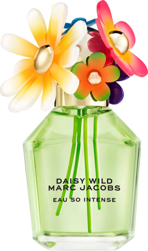Colorful artificial flowers in a green perfume bottle with black text on it.