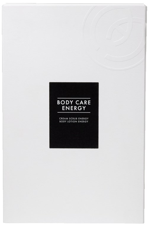 En vit låda med en svart etikett som säger 'BODY CARE ENERGY' och nämner produkter som kroppsscrub och lotion.