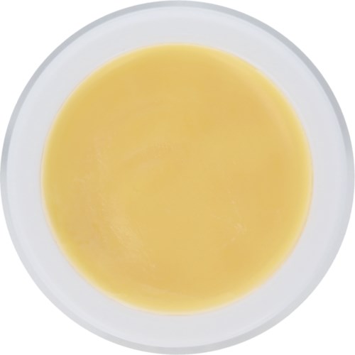 En hvit bolle fylt med gul væske, muligens suppe eller saus, sett ovenfra.