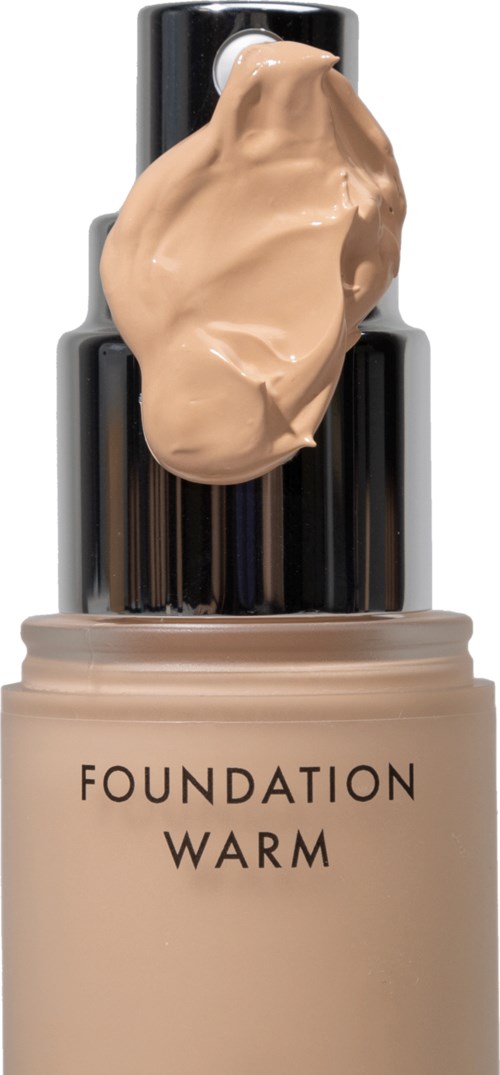 A bottle of foundation labeled 'Warm', with a beige cream on top, and a black cap.