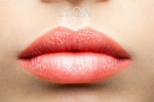 Nærbillede af læber med blankt, lyserødt-orange læbestift. Ordet "LYON" er skrevet over.