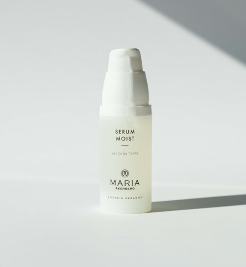 En vit hudvårdsserumflaska med pump, märkt 'Serum Moist' av Maria Akberg, på vit och grå bakgrund.