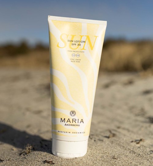 Aurinkovoideputeli, SPF 30, hiekassa selkeän taivaan taustalla.