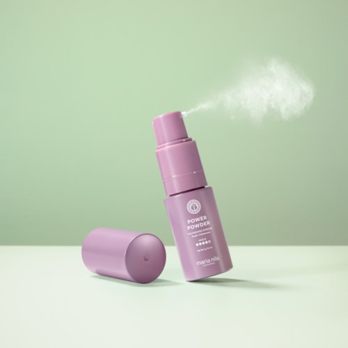 Violetti suihkepullo vapauttaa pilven jauhetta vaaleanvihreällä taustalla.
