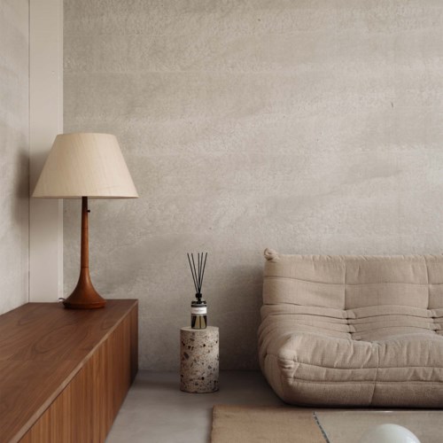 Ein gemütliches Zimmer mit einem Sofa, einer Lampe und einem kleinen dekorativen Objekt auf einem Ständer.
