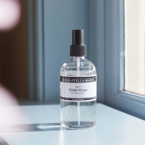 En sprayflaska med svart lock på ett fönsterbräde, märkt Violet Muse av Marie-Stella-Maris.