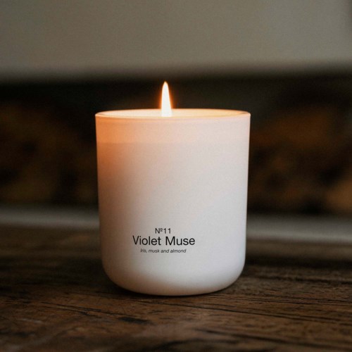 Ett vitt ljus med liten flamma, märkt Violet Muse med doftdetaljer.