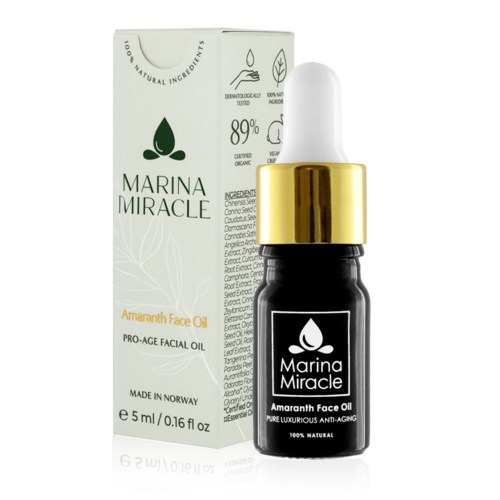 En liten svart flaske med hvit og gull topp, merket 'Marina Miracle Amaranth Face Oil', ved siden av esken.