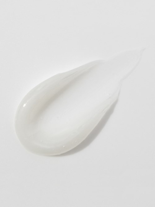 En klick vit grädde eller lotion på en vit yta, slät och glänsande.