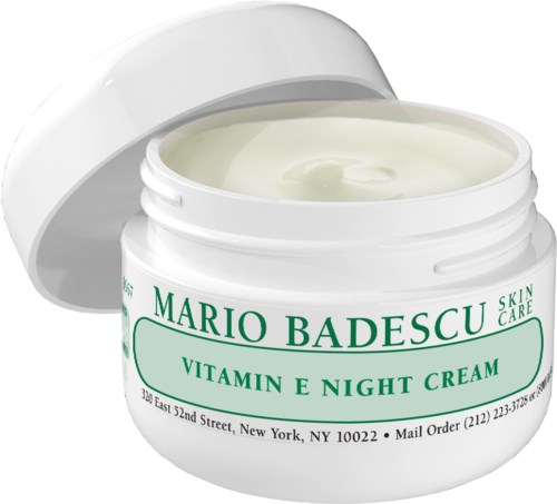 A white jar of night cream with green text, partially open, showing pale cream inside.