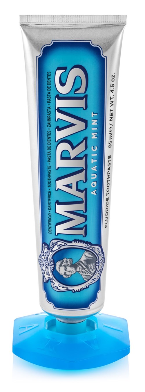 Tuba pasty do zębów Marvis w niebiesko-białym wzorze, ustawiona na niebieskiej podstawce.
